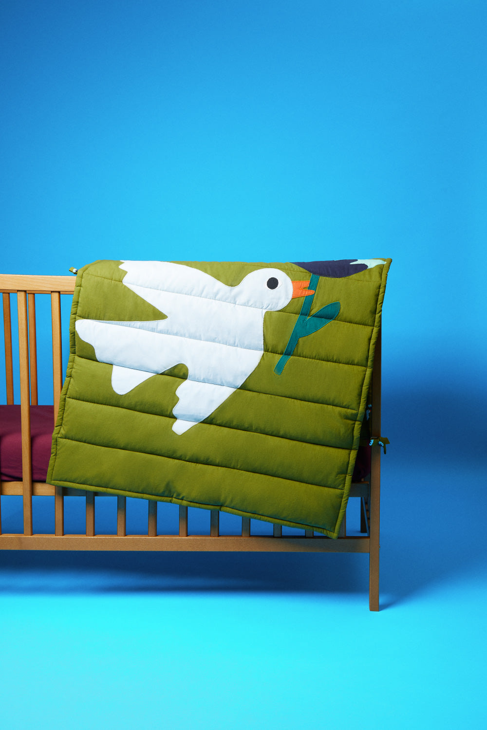 tapis d'éveil pour bébé. Matelassé avec un motif oiseau en patchwork. mise en scène sur un lit bébé. 26 PARADIS